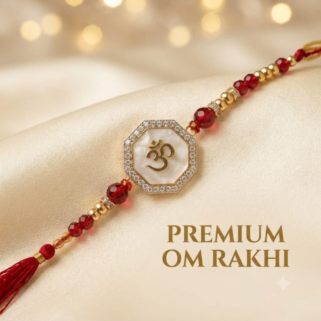 A premium Om Rakhi bracelet laid diagonally on a cream satin fabric background with warm golden bokeh lights. The bracelet features a central octagonal white shell medallion with a gold Om symbol, bordered by small clear stones, flanked by deep red faceted beads and gold spacer beads.