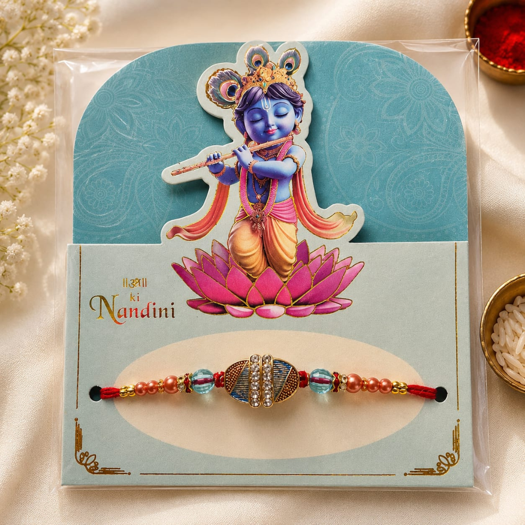 A packaged Nandini Rakhi with a blue and gold central bead, pink and blue side beads, and a decorative card featuring a blue-skinned child playing a flute on a pink lotus.