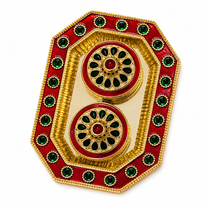 A decorative gold-plated brass tray with red enamel and green stone accents, featuring two circular motifs on a white background.
